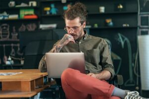 Man with tattoos concentrating on his laptop