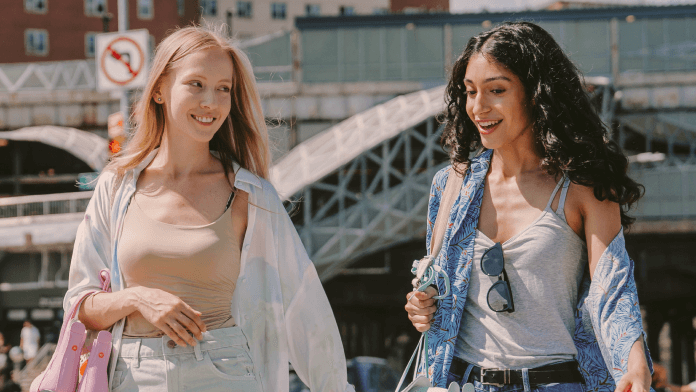 Two young women walking while talking and smiling