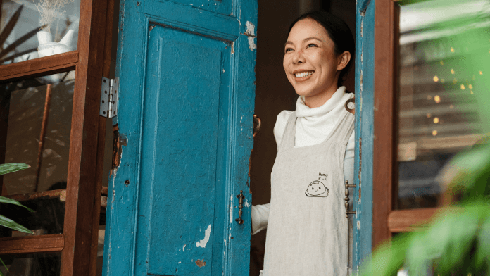 A woman smiling while looking out an open door.