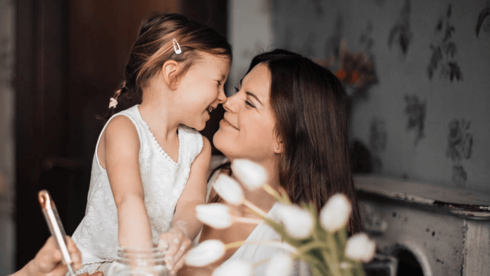 A woman smiling while nose-to-nose with a little girl.